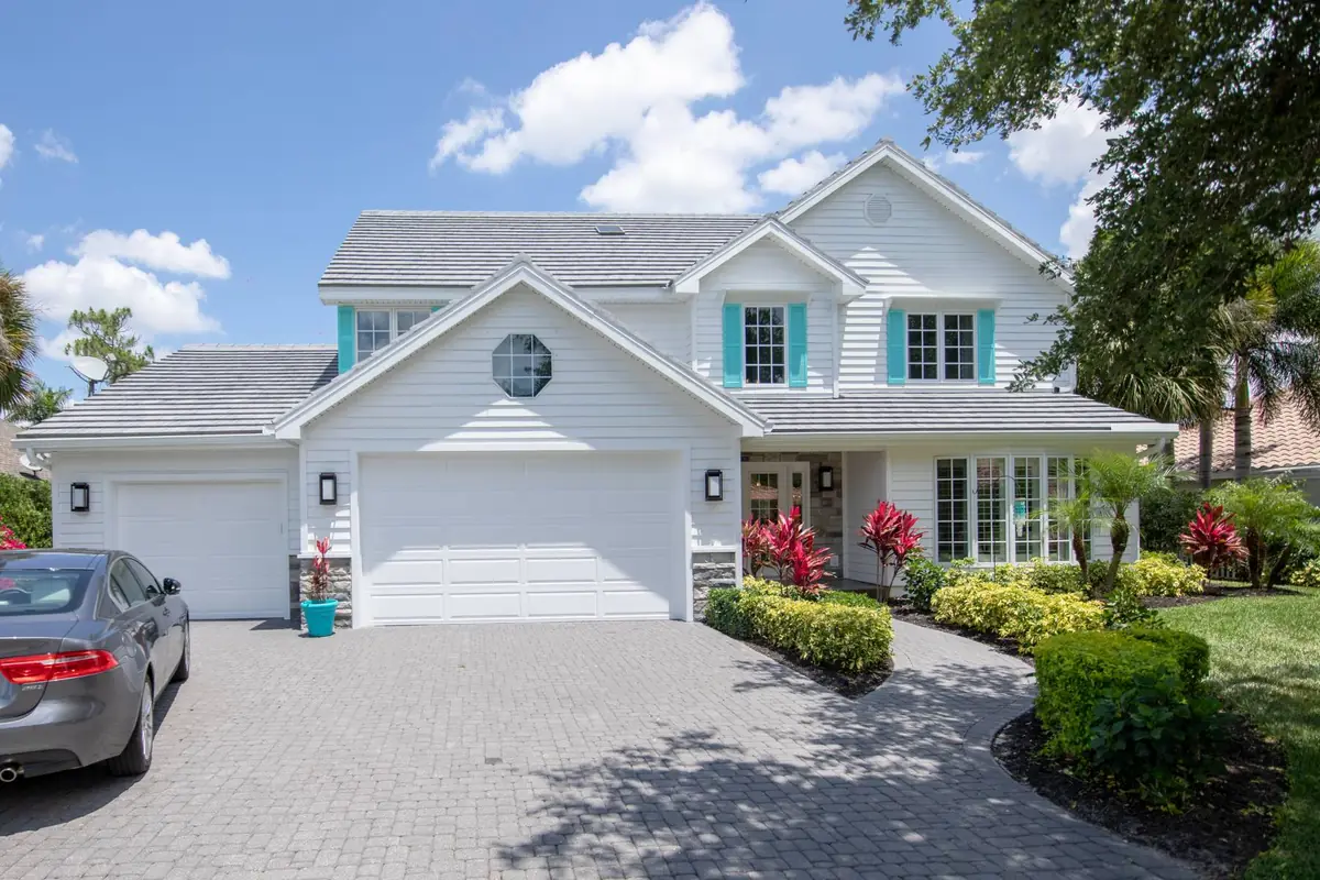 Two-story white home with a gray flat-tile roof and teal shutters